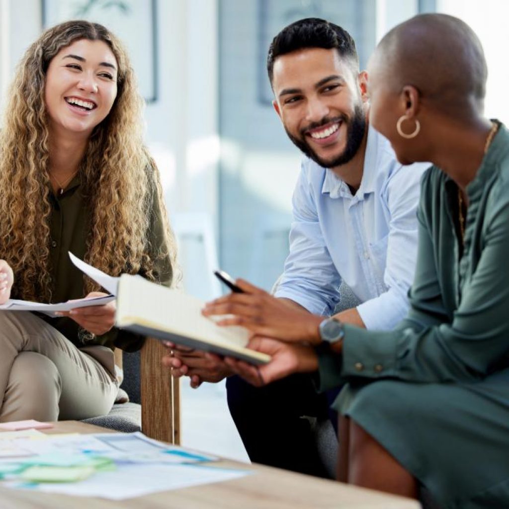 Three professionals sitting in a business casual environment discussing investments