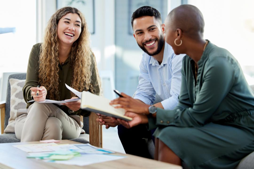 Three professionals sitting in a business casual environment discussing investments